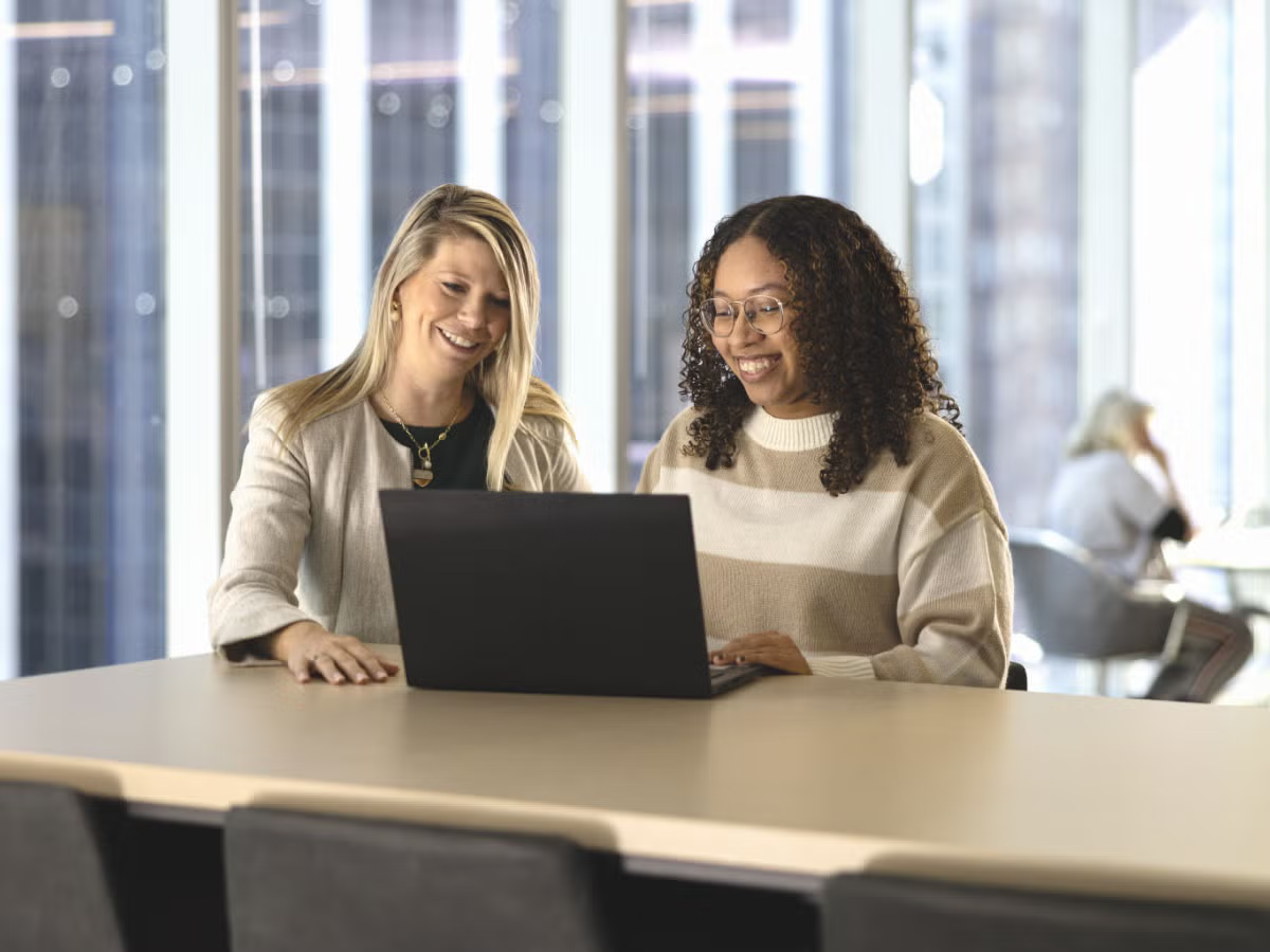 two women facing laptop