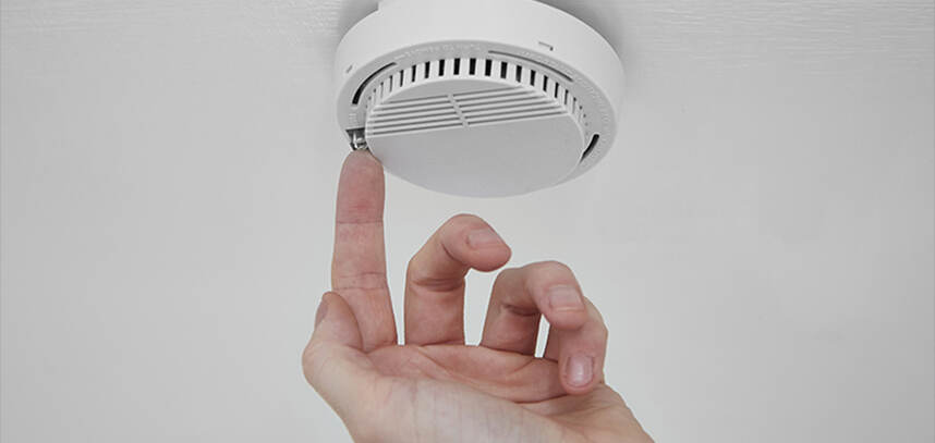 A person pressing a button on a fire alarm. 